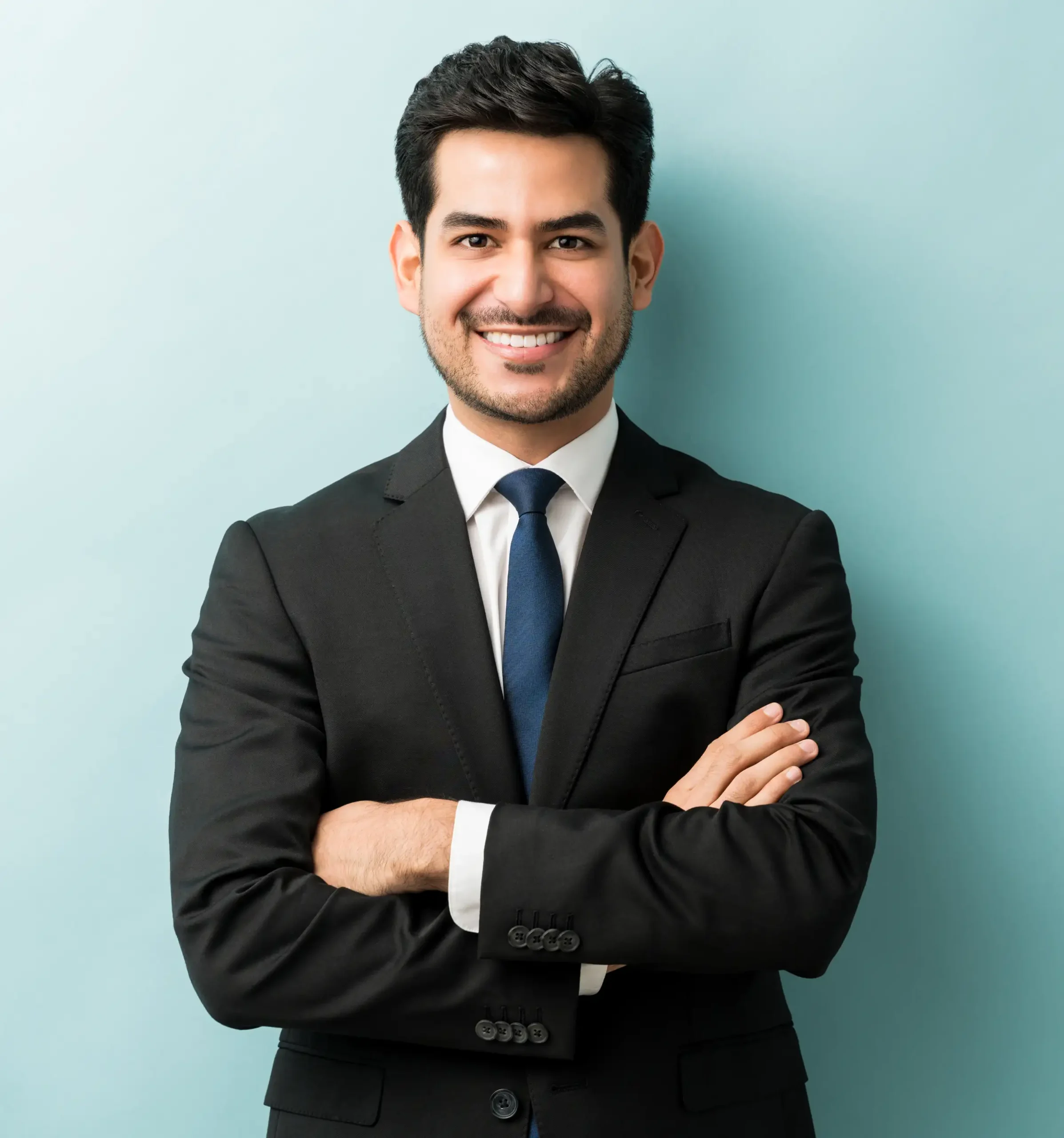 smiling-young-male-professional-standing-with-arms-crossed-while-making-eye-contact-against-isolated-background