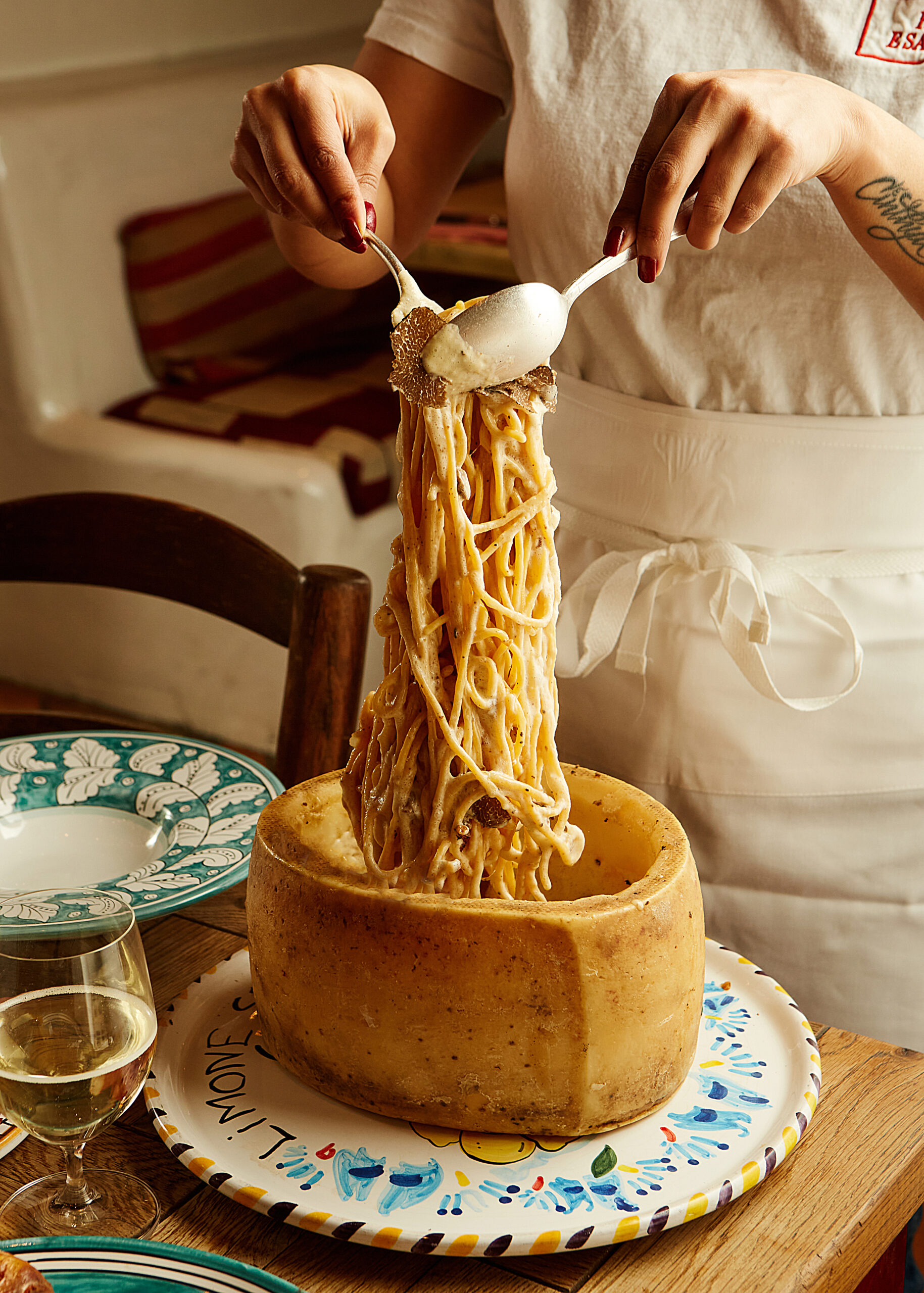 "A waiter prepares Tagliolini al Tartufo Bianco tableside in a pecorino wheel at the luxurious Jacuzzi London restaurant."